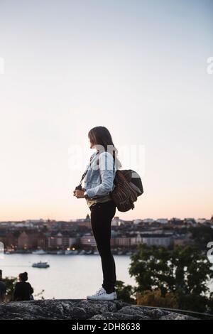 Seitenansicht der weiblichen Touristen, die auf Felsen gegen klar stehen Himmel Stockfoto