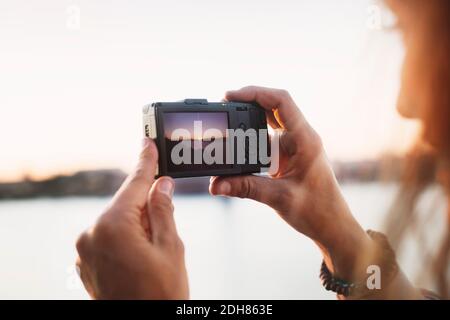 Zugeschnittenes Bild von weiblichen Touristen fotografieren durch Digitalkamera gegen Der Himmel ist klar Stockfoto