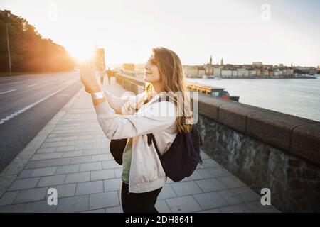 Seitenansicht der weiblichen Touristen, die mit dem Smartphone fotografieren Brücke Stockfoto