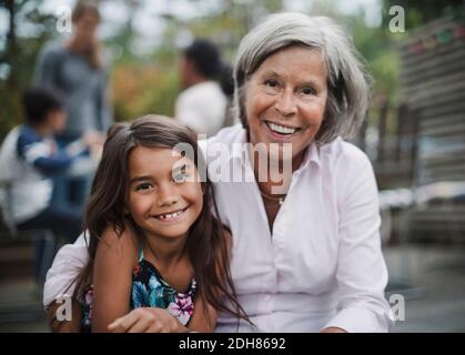 Porträt einer glücklichen Großmutter, die mit Enkelin auf dem Hof sitzt Stockfoto