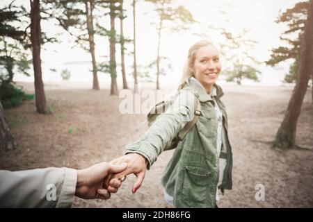 Glückliche Frau, die die Hand des Mannes im Wald hält Stockfoto