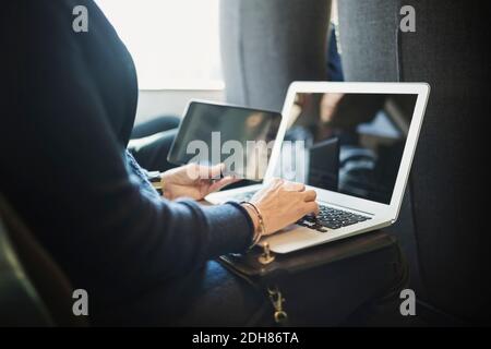 Mittelteil der Geschäftsfrau mit Laptop und Digital-Tablet im Zug Stockfoto