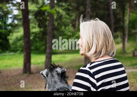 Rückansicht einer glücklichen älteren Frau, die mit Hund sitzt Ein Stockfoto