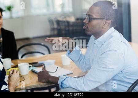 Geschäftsmann, der mit Kollegen im Vorstandszimmer spricht Stockfoto