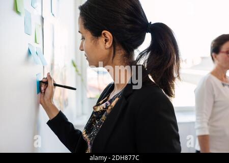 Geschäftsfrau schrieb in einem Haftnotiz an die Wand im Konferenzraum Stockfoto