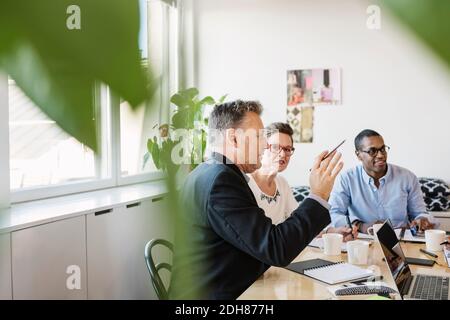 Reifer Geschäftsmann erklärt Multi ethnischen Kollegen während des Treffens Stockfoto