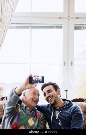 Glücklicher Mann nimmt Selfie mit jungen Hausmeister im Pflegeheim Stockfoto