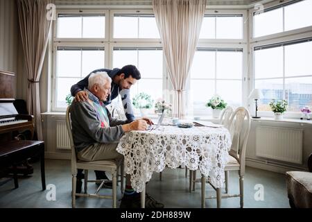 Älterer Mann mit Laptop und Hausmeister im Pflegeheim Stockfoto