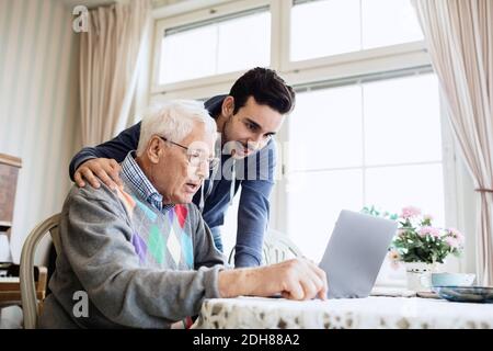 Hausmeister und Senior Mann mit Laptop im Pflegeheim Stockfoto