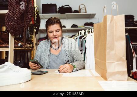 Geschäftsfrau Berechnung auf dem Tisch im Bekleidungsgeschäft Stockfoto