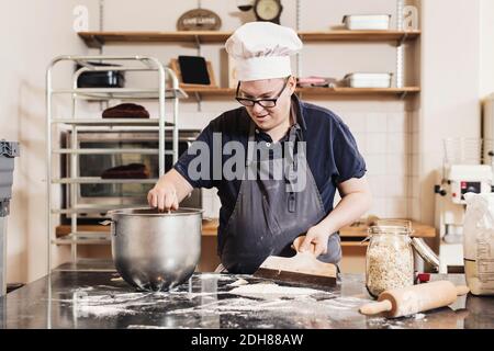Junger Mann, der Teig an der Küchentheke macht Stockfoto