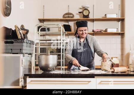 Glückliche weibliche Bäcker machen Teig auf Küchentisch Stockfoto