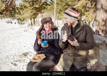 Pärchen, die im Winter auf Felsen sitzen und essen Stockfoto