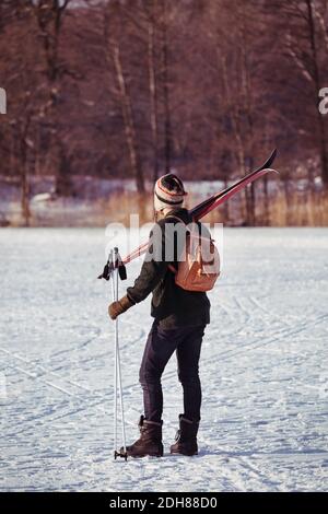 Rückansicht des männlichen Wanderers, der die Skiausrüstung auf dem Feld trägt Stockfoto