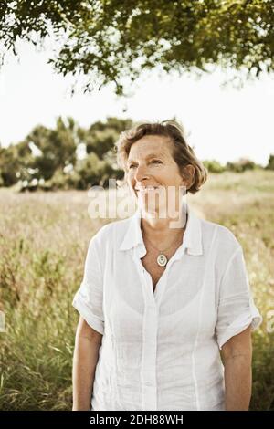 Vorderansicht einer lächelnden reifen Frau, die im Grasland steht Stockfoto
