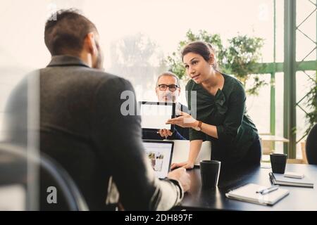 Geschäftsfrau, die ihre Ideen auf einem digitalen Tablet dem Manager in vorstellt Büro Stockfoto