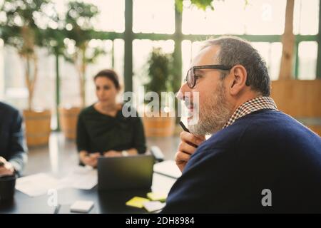 Konzentrierter reifer Geschäftsmann in der Sitzung im kreativen Büro Stockfoto