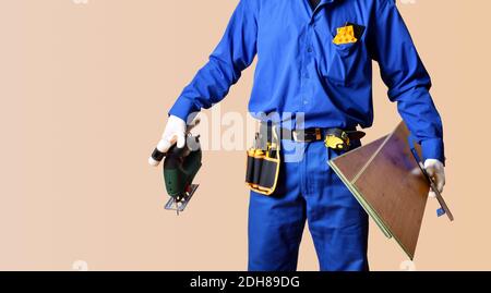 Hintergrund Detail des Körpers eines Parkett-Installateur in Overalls gekleidet und mit Werkzeugen und Parkettbohlen versehen. Horizontale Zusammensetzung. Stockfoto