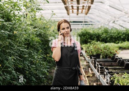 Gärtnerin spricht im Gewächshaus mit dem Handy Stockfoto