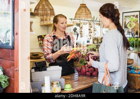 Kundin im Gespräch mit Kassiererin im Reformhaus Stockfoto