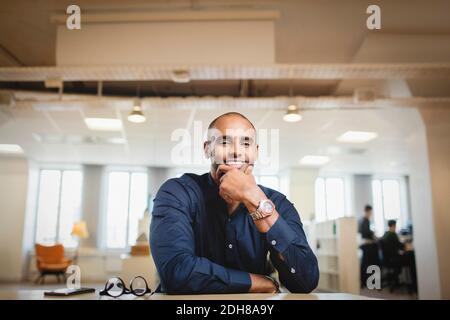 Porträt eines lächelnden Mannes mit der Hand auf dem Kinn sitzend Tabelle Stockfoto