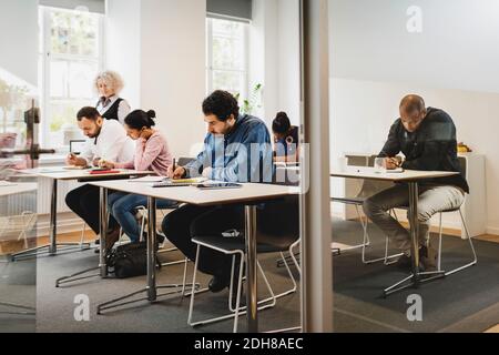 Lehrer, der Schüler ansieht, die in der Sprachklasse schreiben Stockfoto