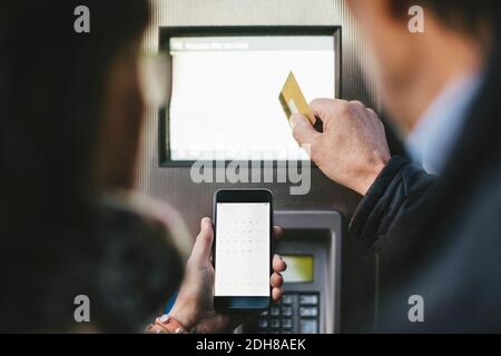 Ältere Paare, die die Zahlung per Kreditkarte und Mobiltelefon vornehmen An der Fahrradverleihstation Stockfoto