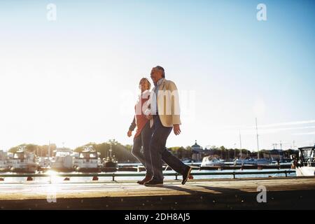 Ein liebevolles Senioren-Paar, das auf dem Pier gegen läuft Himmel Stockfoto