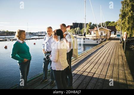 Zwei ältere Paare, die sich unterhalten, während sie auf dem Pier stehen Stockfoto