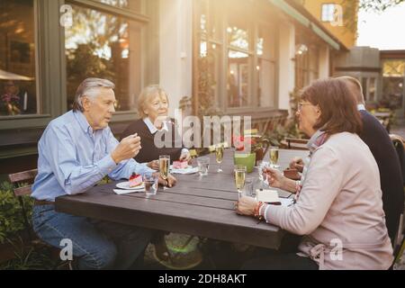 Zwei ältere Paare, die Desserts im Restaurant im Freien essen Stockfoto