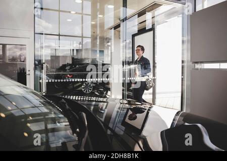 Ältere Frau durch Glas gesehen, die in den Autosalon eintrat Stockfoto