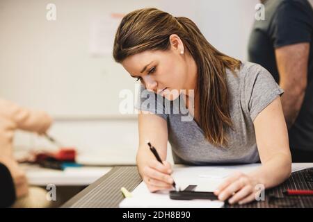 Weibliche Ingenieurplanung auf Papier mit Kollegen im Hintergrund Stockfoto