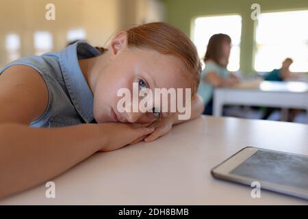 Schulmädchen lehnte sich in einem Schulunterricht auf ihren Schreibtisch Stockfoto