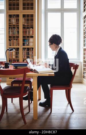 Anwältin mit Laptop, während sie an einem Tisch in der Bibliothek sitzt Stockfoto