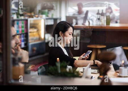 Geschäftsfrau mit Telefon in der Sitzung durch Glas bei kreativ gesehen Büro Stockfoto