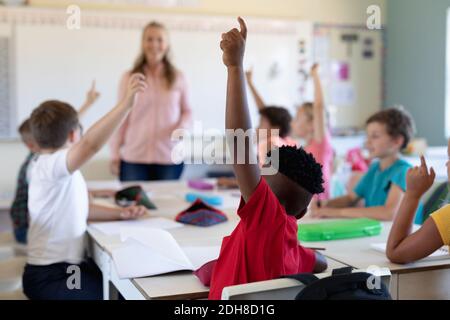Gruppe von Schulkindern, die ihre Hände in einem Schulunterricht heben Stockfoto