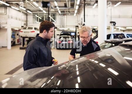 Mechaniker im Gespräch, während sie in der Autowerkstatt stehen Stockfoto