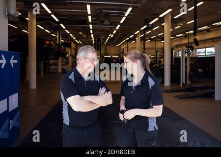 Glückliche Experten diskutieren, während an der Auto-Reparatur-Shop stehen Stockfoto