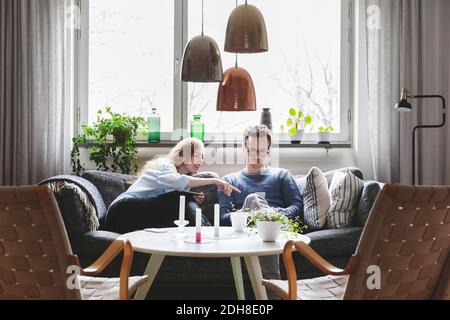 Koppeln Sie sich mit Technologien, während Sie zu Hause auf dem Sofa sitzen Stockfoto