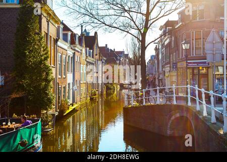 Blick auf die Straße mit Häusern und Kanal in Delft, Holland bei Sonnenuntergang Stockfoto