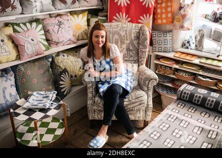 Portrait von selbstbewussten weiblichen Besitzer sitzt auf Stuhl an Stoff Kaufen Stockfoto