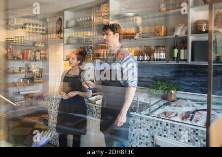 Seriöse Besitzer arbeiten in Fischgeschäft durch Glas gesehen Stockfoto