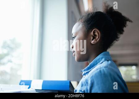 Nahaufnahme eines nachdenklichen Mädchens, das durch das Fenster im Klassenzimmer schaut Stockfoto