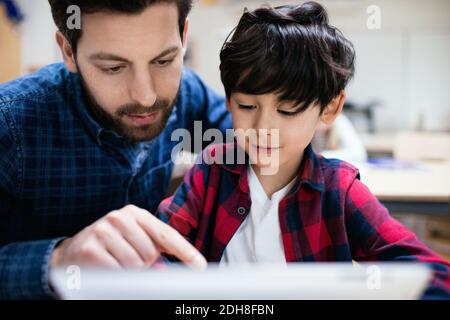 Nahaufnahme des Lehrers, der neugierigen Schüler im Klassenzimmer erklärt Stockfoto