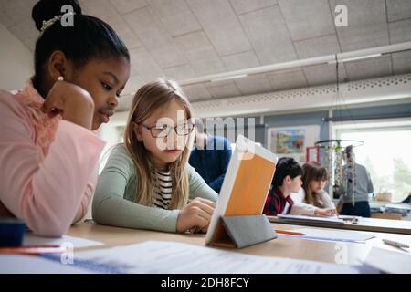 Schülerinnen lesen digitale Tablet am Schreibtisch im Klassenzimmer Stockfoto