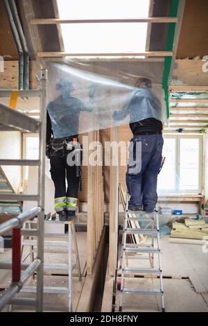 Niedrige Ansicht der Arbeiter, die an der Holztür arbeiten Auf der Baustelle Stockfoto