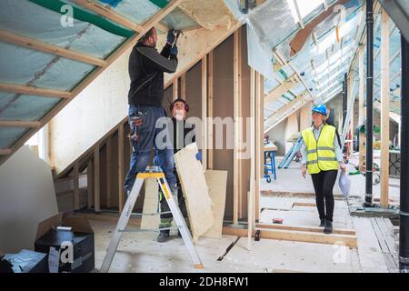 Weibliche Managerin, die sich die auf der Baustelle arbeitenden Arbeiter ansieht Stockfoto