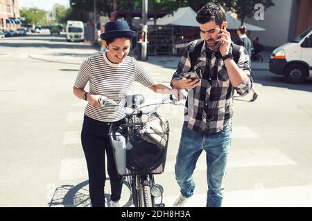 Mann, der Smartphone benutzt, während er mit Frau auf der Straße läuft Stockfoto