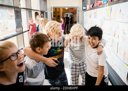 Kippen Sie Aufnahme der fröhlichen Freunde im Schulkorridor Stockfoto