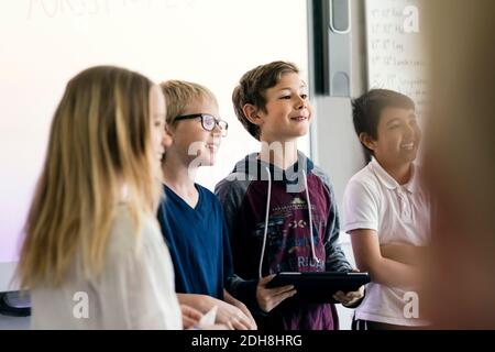 Glückliche Schüler halten Präsentation mit digitalen Tablet im Klassenzimmer Stockfoto